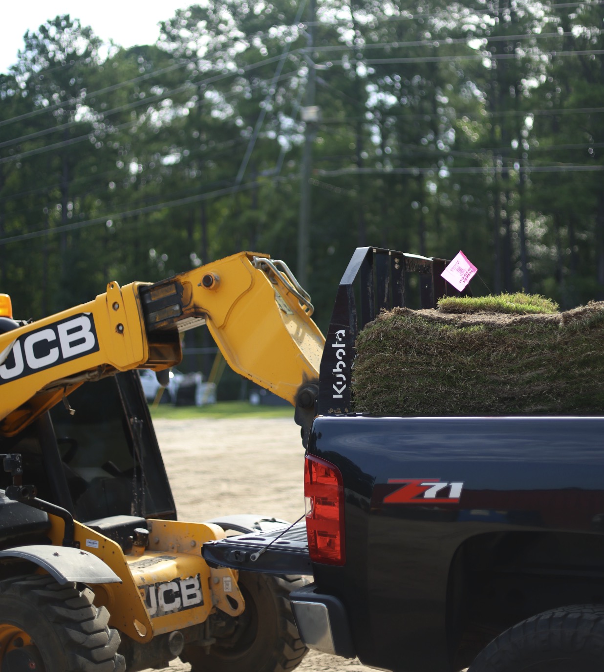 Telehandler loading a pallet of sod into a pickup bed at the yard