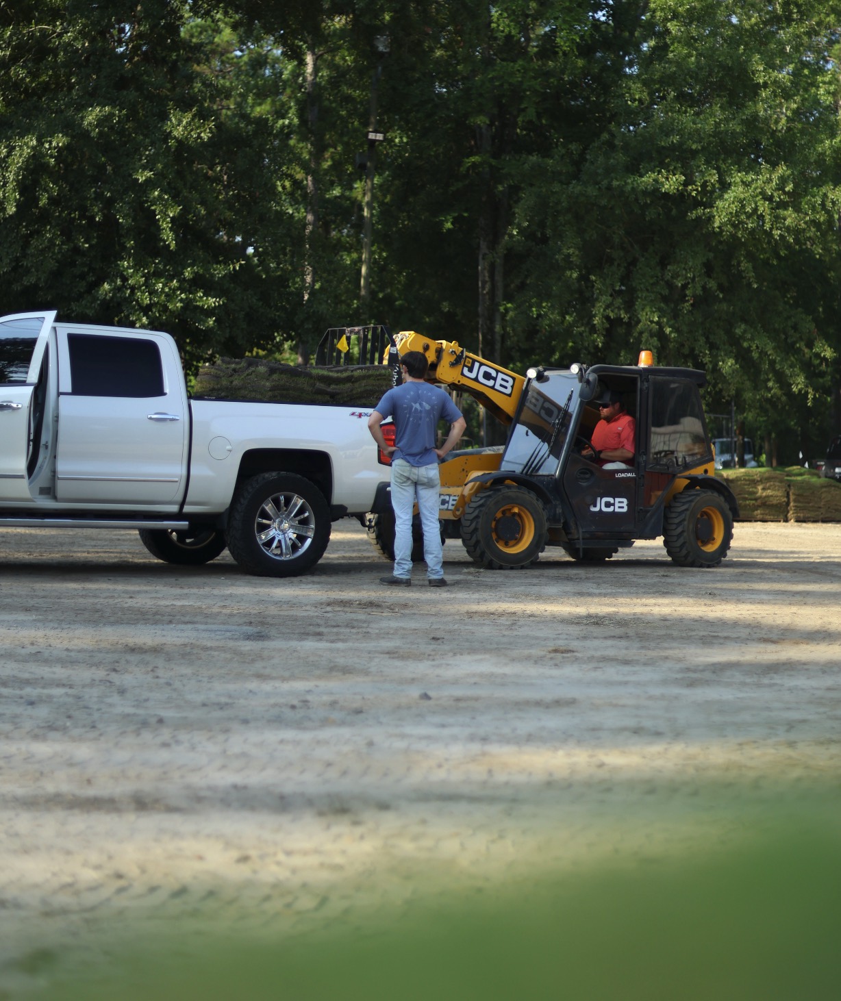 A customer's pickup being loaded with sod by a telehandler at the yard